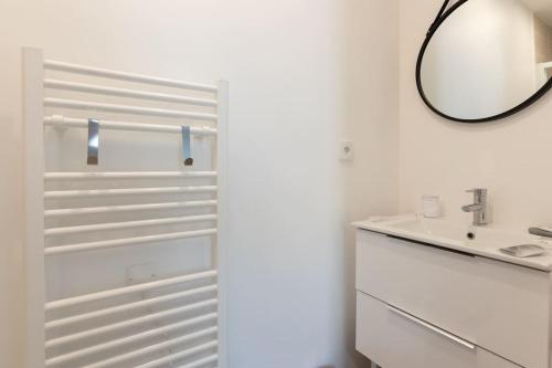 a white bathroom with a sink and a mirror at T2 plain-pied à 3 minutes du centre in Castres