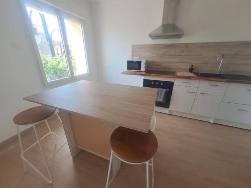 une cuisine avec une table en bois et deux chaises dans l'établissement T3 rénové vue mer, au Barcarès