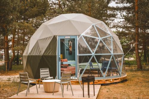 une tente en forme de dôme géodésique avec des chaises et une table dans l'établissement Čiki Puki Glamping, à Palanga