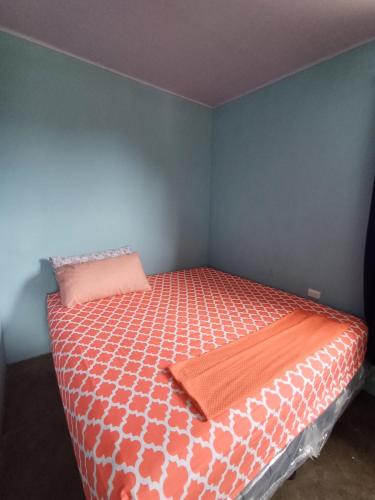 a small bedroom with a bed with an orange blanket at House la Rosa third floor 5 in Quepos