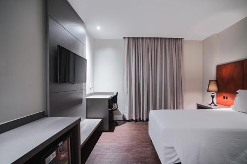 a hotel room with a bed and a television at Brut by Slaviero Hotéis in Balneário Camboriú