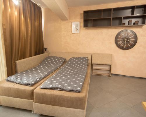 une chambre avec un canapé et un réveil sur le mur dans l'établissement Aleks Holiday-center,sea,parking, à Bourgas