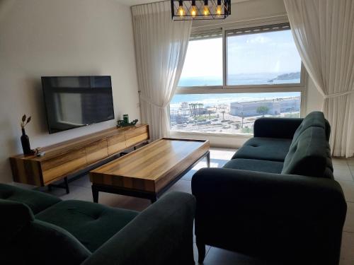 a living room with couches and a television and a table at Ducks on the beach in ‘Akko