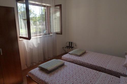 two twin beds in a room with a window at House Meli in Rakalj