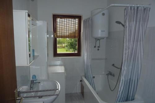 a white bathroom with a shower and a sink at House Meli in Rakalj