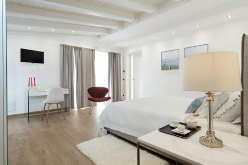 a white bedroom with a bed and a table with a lamp at Camemi in Seccagrande