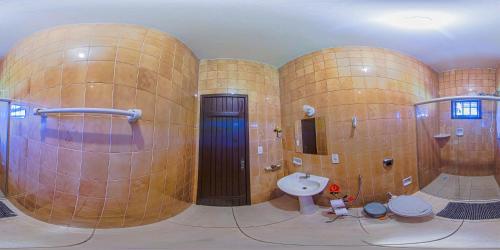 La salle de bains est pourvue de murs en bois, de toilettes et d'un lavabo. dans l'établissement Pousada Minas Goiás, à Tiradentes
