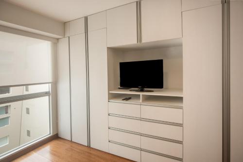 a living room with a tv and white cabinets at Las Mimosas by Wynwood House in Lima