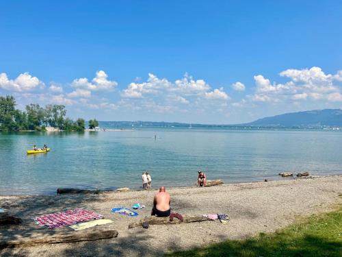 a man sitting on the shore of a lake at Seeparkvilla – Wohlfühlen am See und im Grünen in Bregenz