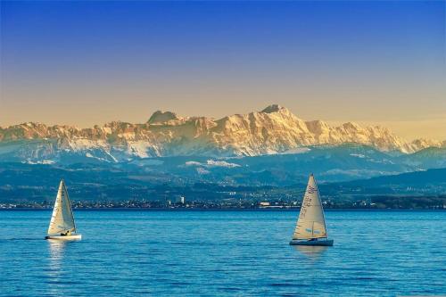 two sailboats in the water with a mountain in the background at Seeparkvilla – Wohlfühlen am See und im Grünen in Bregenz