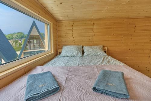 1 dormitorio con 1 cama con 2 almohadas y ventana en Domki RWL en Rewal