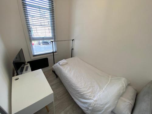 1 dormitorio con cama blanca y mesa blanca en Small Single room walking distance to Hove Station, en Brighton & Hove