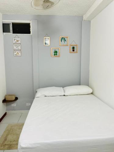 a white bedroom with a white bed and pictures on the wall at HOSTAL AMA in Leticia