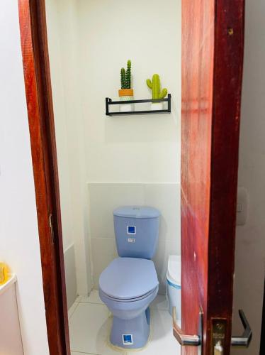 een badkamer met een blauw toilet en een plant op een plank bij HOSTAL AMA in Leticia