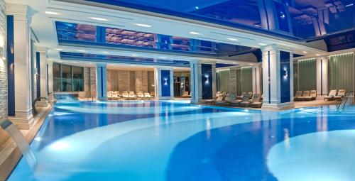 a large swimming pool in a hotel with blue lighting at Sueno Hotels Deluxe Belek in Belek