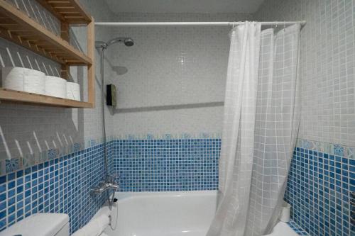Un baño con azulejos azules, bañera y ducha. en Apartamento Cala Grande, en La Isleta del Moro
