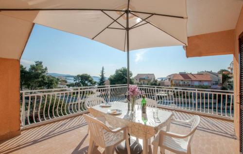 a table and chairs with an umbrella on a balcony at Slavica Olive 3 in Brodarica