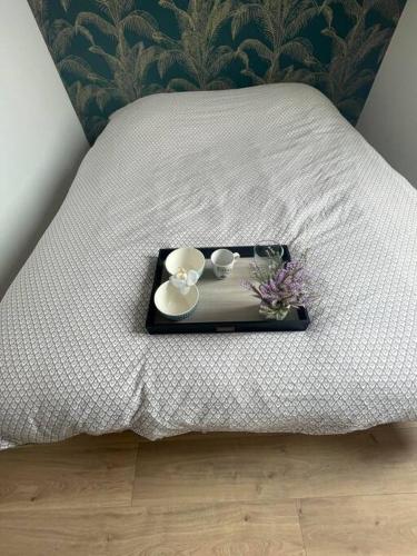 un vassoio con due tazze e fiori su un letto di appartement 2 neuf climatisée a Blaye