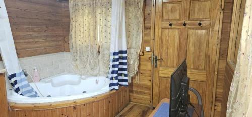 ein Bad mit einer Badewanne und einem TV in der Unterkunft נופש דביר - סוויטות מקסימות ובקתה כפרית עם ג'קוזי ליד הכנרת - יש מקלט צמוד in Migdal