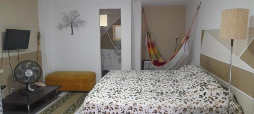 um quarto com uma cama, uma cadeira e uma televisão em Loft 2 Quadras da Praia no Rio de Janeiro