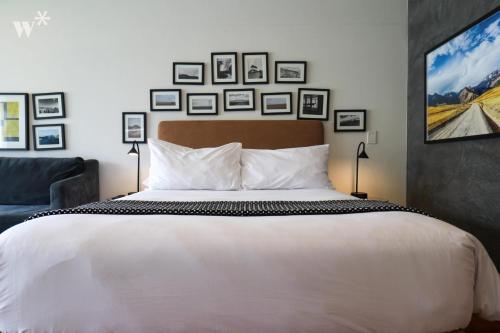 a bedroom with a large white bed and pictures on the wall at Las Mimosas by Wynwood House in Lima