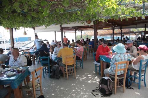 a group of people sitting at tables in a restaurant at Paralia guest house in Agia Roumeli