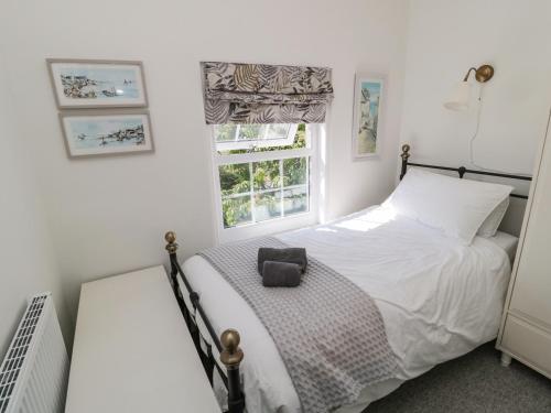 a white bedroom with a bed and a window at 9 Station Cottages in Belford