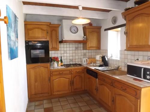 une cuisine avec des armoires en bois et un four à plaques de cuisson dans l'établissement GITE RURAL FINISTERE SUD ENTREE PRESQUI'LE CROZON, à Saint-Ségal
