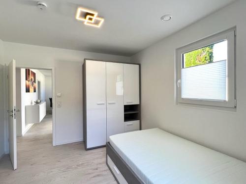 biała sypialnia z łóżkiem i oknem w obiekcie Apartment Brochenzell - nahe Ravensburger Spieleland w mieście Meckenbeuren
