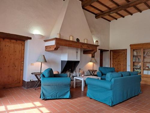 a living room with two blue chairs and a fireplace at Fattoria Lornano Winery in Monteriggioni