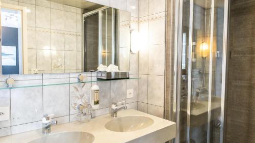 a bathroom with two sinks and a mirror at Hotel Europe Brig in Brig