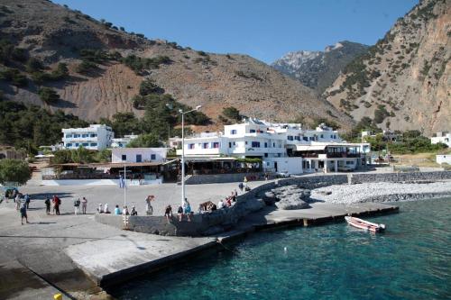 a group of people walking on a dock in the water at Paralia guest house in Agia Roumeli
