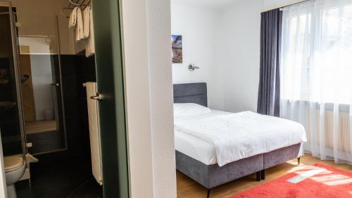 a bedroom with a bed and a bathroom with a window at Hotel Europe Brig in Brig