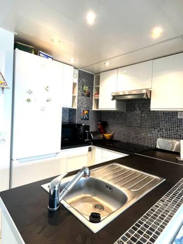 - une cuisine avec un évier et des placards blancs dans l'établissement Super t 3, vue mer piscine clim, au Barcarès