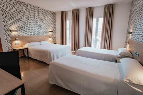 a hotel room with two beds and a table at Atenas Granada in Granada