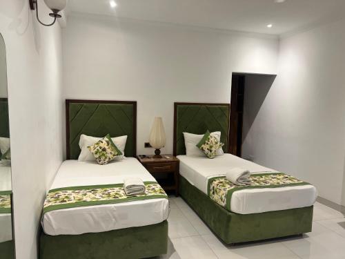 a bedroom with two beds and a table with a lamp at Gatetrees resort in Jaffna