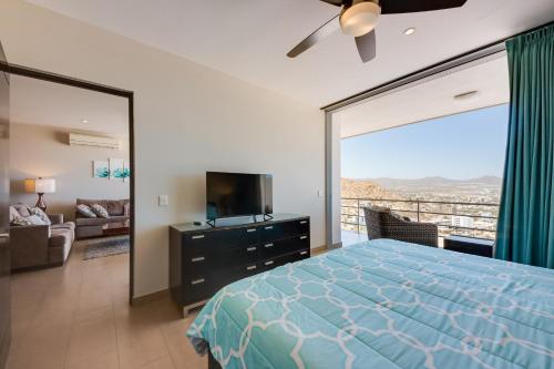 Schlafzimmer mit einem Bett, einem TV und einem Balkon in der Unterkunft Cabo Pedregal Condo Ocean View and 2 Infinity Pools in Cabo San Lucas