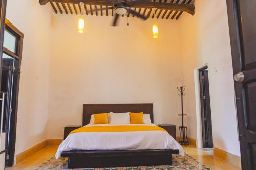 - une chambre dotée d'un lit avec des draps jaunes et blancs dans l'établissement Casa en Zona Centro, Campeche., à Campeche