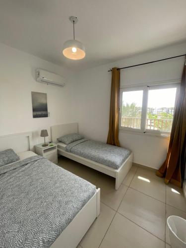 a bedroom with two beds and a window at Almaza Bay Beach Town Chalet in Marsa Matruh