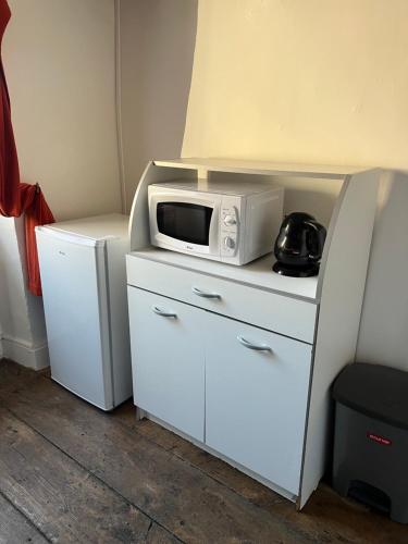 un microondas sentado en la parte superior de un armario blanco en Studio, chambre privée, en Langres