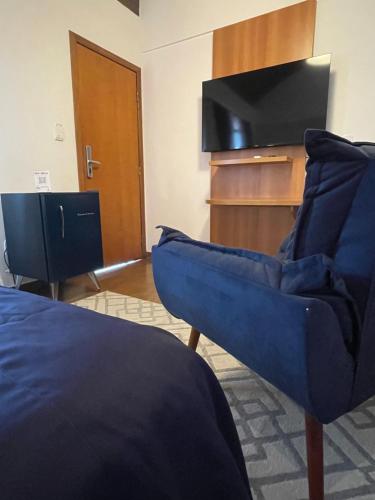 a living room with a tv and a blue couch at Hotel Aromas de Penedo in Penedo