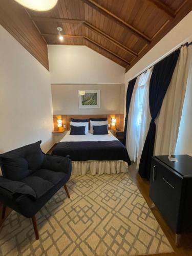 a bedroom with a bed and a chair in a room at Hotel Aromas de Penedo in Penedo