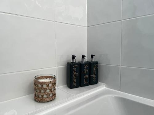 a bath tub with three black bottles and a basket at Beachfront retreat apartment with amazing terrace in Hastings