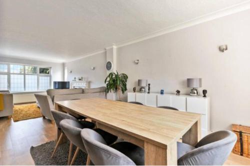 a dining room with a wooden table and chairs at Large family home near Richmond Park in New Malden