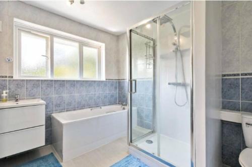 a bathroom with a shower and a tub and a sink at Large family home near Richmond Park in New Malden