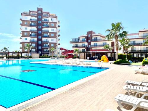 a swimming pool with lounge chairs and a building at Royal Sun NETFLIX Residence, Long Beach Design Apartment - no utility expenses! in Yeni Iskele