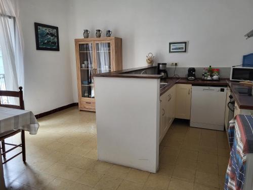 a kitchen with a white island in a room at L'Escala - Pintor Massanet in L'Escala