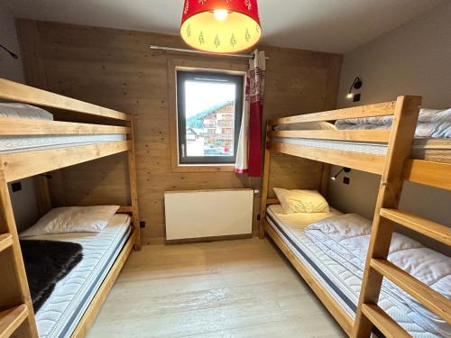 une chambre avec trois lits superposés et une fenêtre dans l'établissement Appartement neuf aux Gets, au pied des pistes et du centre, avec terrasse et services inclus - FR-1-623-50, aux Gets