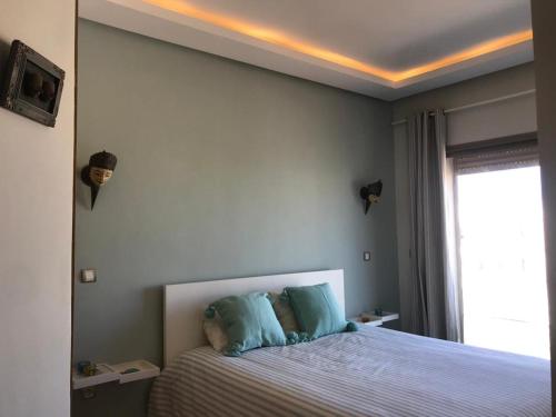 Bouznika plage costa في بوزنيقة: غرفة نوم بسرير كبير مع وسائد زرقاء