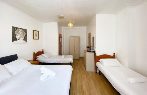 two beds in a room with white walls and wooden floors at Orlando hotel in London